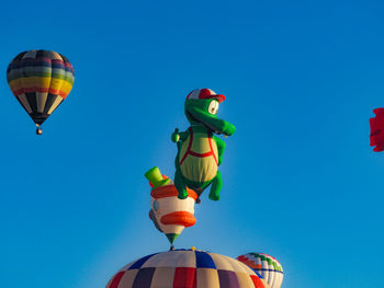 Low angle view of balloons against clear blue sky