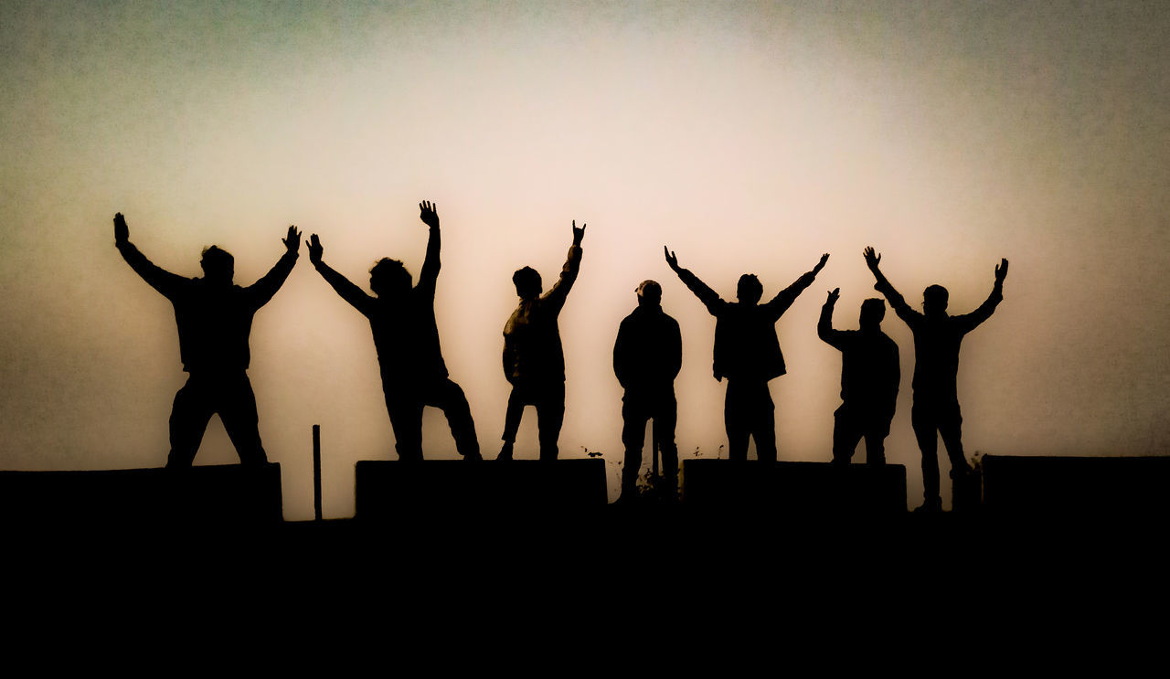 SILHOUETTE PEOPLE STANDING AGAINST SKY WITH ARMS RAISED