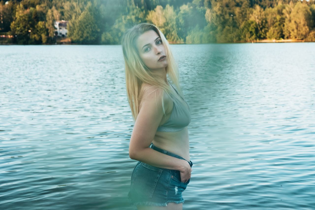 water, young adult, young women, one person, standing, leisure activity, beauty, lifestyles, real people, three quarter length, beautiful woman, long hair, hair, lake, portrait, blond hair, beauty in nature, day, hairstyle, contemplation, outdoors, teenager