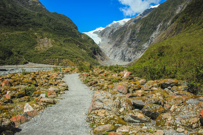 Scenic view of stream amidst mountains against sky