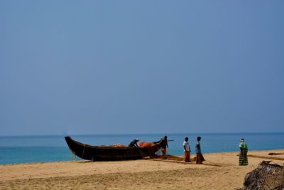 Fishermen standing at beach against sky