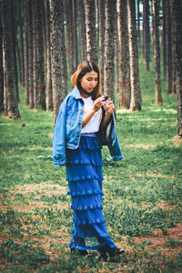 Young woman standing on tree trunk in forest