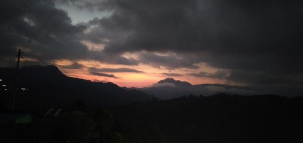 Scenic view of silhouette mountains against dramatic sky