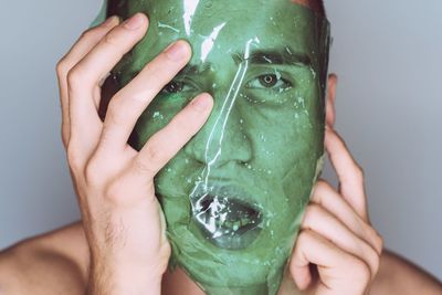 Close-up portrait of serious young man with green plastic on face