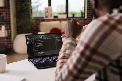 Midsection of man using laptop at home