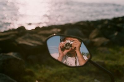 Close-up of girl photographing sea against sky