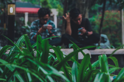 Full length of young man using phone while sitting on land