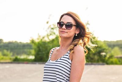 Portrait of smiling young woman wearing sunglasses standing outdoors