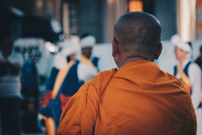 Rear view of monk wearing orange traditional cloth in city