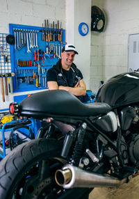 Portrait of smiling mature mechanic cleaning motorcycle in garage