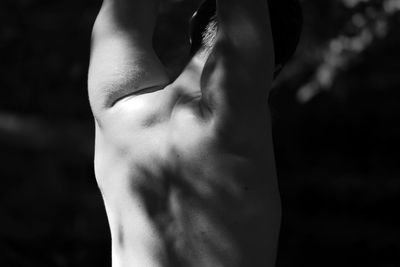 Rear view of shirtless young man stretching outdoors