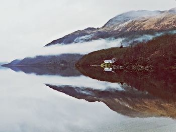 Scenic view of lake by snowcapped mountains against sky