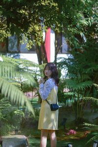 Rear view of woman with arms outstretched standing in park