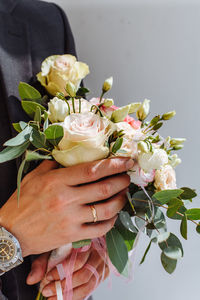 Cropped hand of woman with man holding rose bouquet