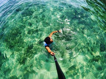 High angle view of man holding monopod while swimming in sea