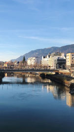 Buildings by lake against sky in city