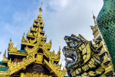 Low angle view of statue amidst buildings against sky