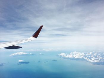 Airplane flying over clouds against sky