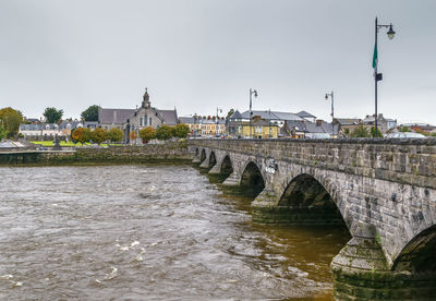 Arch bridge over river against sky in city