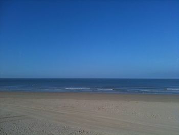 Scenic view of beach against blue sky