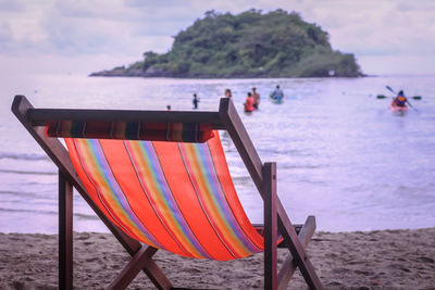 Deck chairs on beach against sky