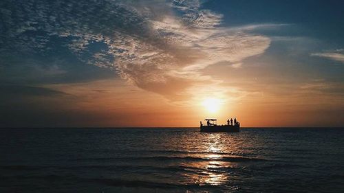 Boat sailing in sea at sunset