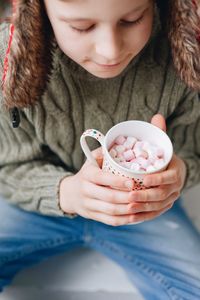 High angle view of girl holding cup while sitting at home