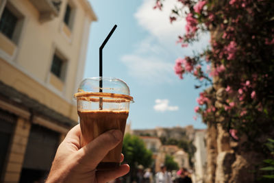 Close-up of hand holding drink against sky