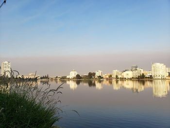 Buildings by river against sky in city