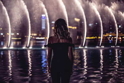 Rear view of woman looking at illuminated city at night