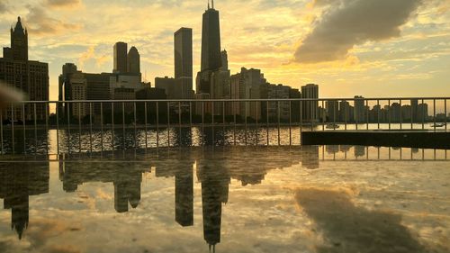 Reflection of buildings in city at sunset