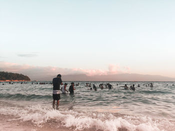 People on beach against sky during sunset