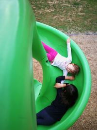 High angle view of siblings playing on slide at playground