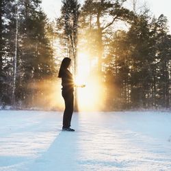 Woman on snow covered landscape during sunset