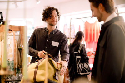 Salesman showing luggage bag to male customer at store