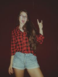 Portrait of beautiful young woman standing against red wall