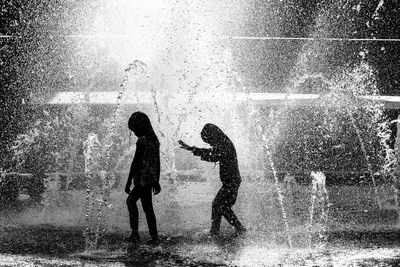 Silhouette man and woman standing in water during rainy season