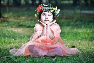 Happy girl sitting on field for festival 