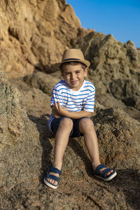 Full length of boy sitting on rock