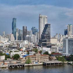 River by buildings in city against sky
