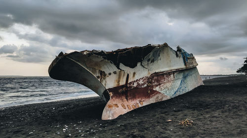 View of abandoned boat on beach against sky