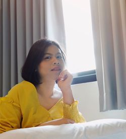 Portrait of beautiful young woman lying on bed at home