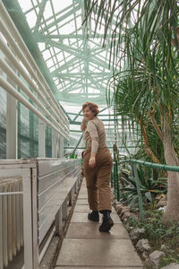 A beautiful plus size girl runs across greenhouse among the green plants. cottagecore style.
