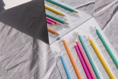 High angle view of colored pencils on table by mirror