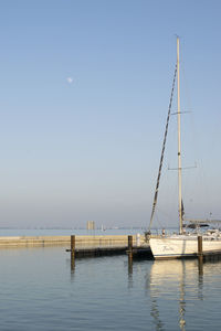 Sailboats moored in sea against clear sky