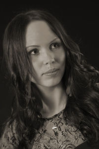 Beautiful young woman looking away against black background