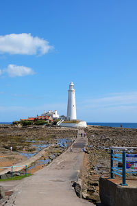 Lighthouse by sea against sky