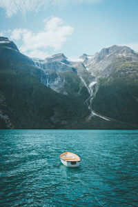 Sailboat in sea against mountains