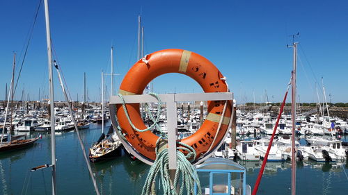 Sailboats moored at harbor against clear sky