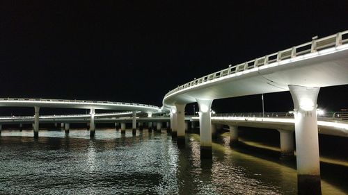 Illuminated bridge against clear sky at night